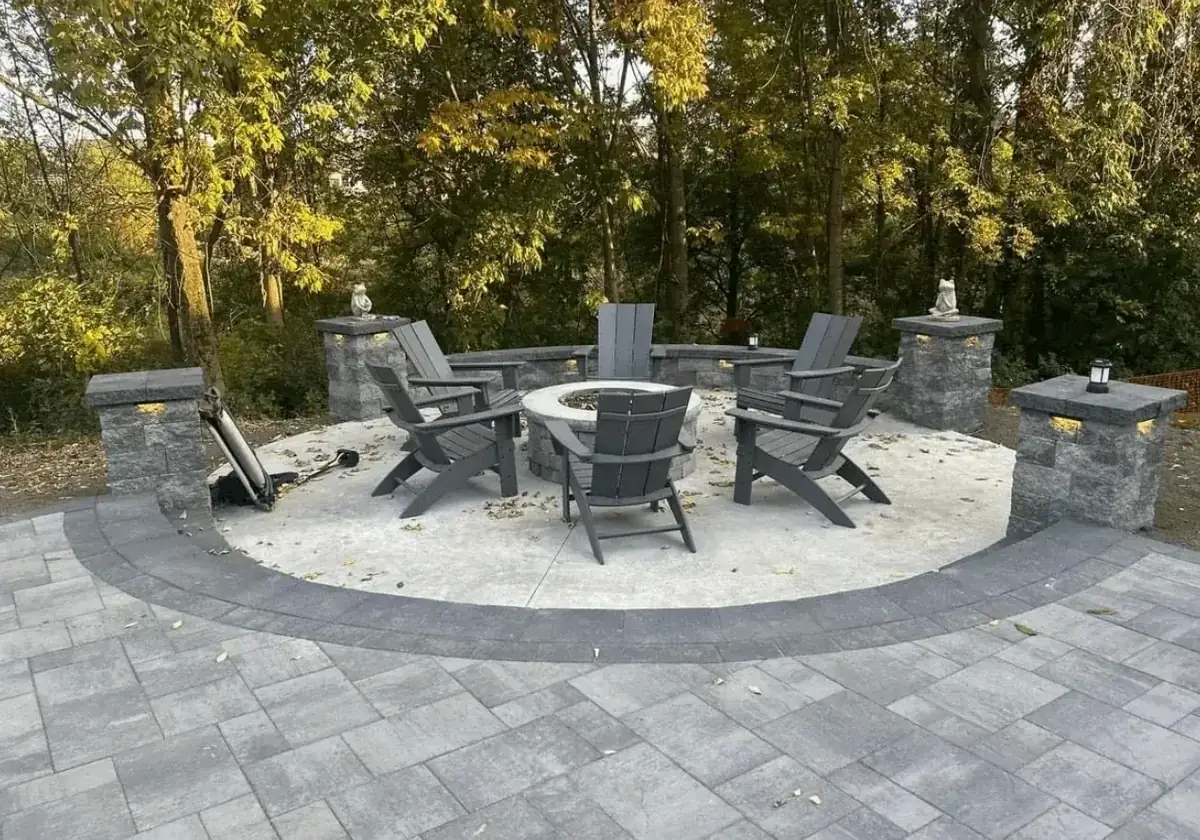 Circular concrete fire pit patio with block seat walls, lighted columns and a paver surround built by Liberty Pour Concrete