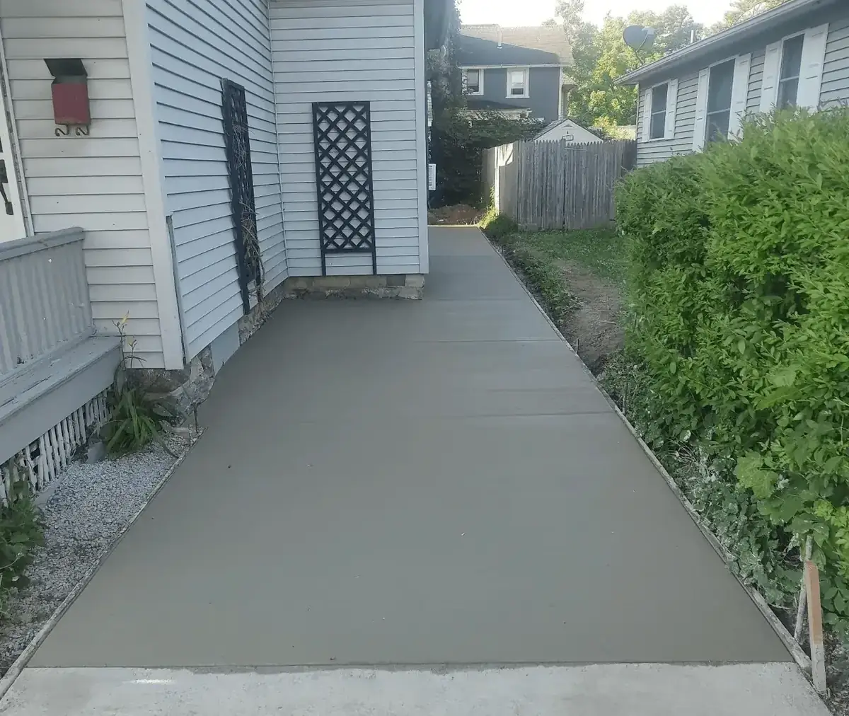 Wide concrete walkway poured along the side of a home in East Aurora NY by Liberty Pour Concrete