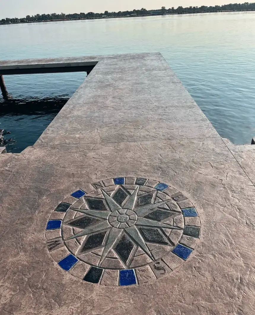 Stamped and stained concrete waterfront deck with a custom compass rose medallion on Grand Island NY by Liberty Pour Concrete